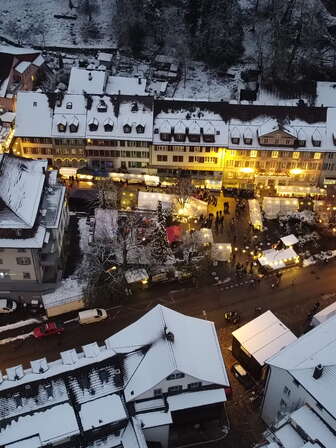 Luftaufnahme von Aarburg bei Dämmerung mit verschneiten Dächern, beleuchteten Marktständen und zahlreichen Besuchern am Anlass «Aarburg leuchtet».