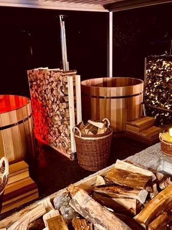 Holzbefeuerte Hotpots am Hallwilersee mit Brennholz und stimmungsvoller Beleuchtung.