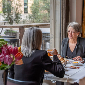 Zwei Frauen geniessen ein gemütliches Frühstück mit frischen Brötchen und Früchten im Limmathof in Baden und Ennetbaden.