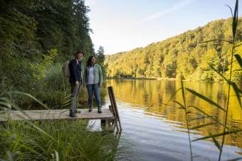 Zwei Personen auf einem Spaziergang am Egelsee, die Personen stehen auf einen Holzsteg und blicken in die Natur.