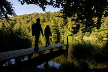 Zwei Personen auf einem Spaziergang am Egelsee, die Personen stehen auf einen Holzsteg und blicken in die Natur.