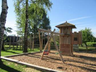 naturnaher kinderspielplatz ruetihof mit holzspielturm, schaukeln und kletterelementen im gruenen