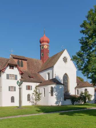blick auf die historische klosteranlage wettingen mit kirche, turm und gruener klosterwiese.