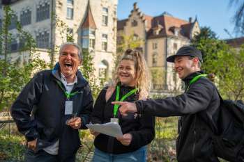 Drei Teilnehmende des Foxtrail Aarau lachen und lösen gemeinsam Aufgaben in der Altstadt. Die historische Kulisse und die Freude am Rätseln stehen im Mittelpunkt des Stadtabenteuers.
