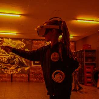 Kind mit VR-Brille und Controller erlebt ein Virtual-Reality-Spiel in einem stimmungsvoll beleuchteten Raum in Zofingen