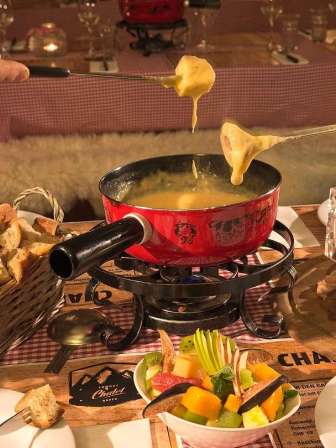 Kaesefondue mit Brot, Wein und frischen Beilagen im Fondue Chalet des Restaurant Lemon in Baden.