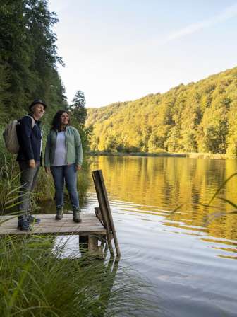 Zwei Personen auf einem Spaziergang am Egelsee, die Personen stehen auf einen Holzsteg und blicken in die Natur.