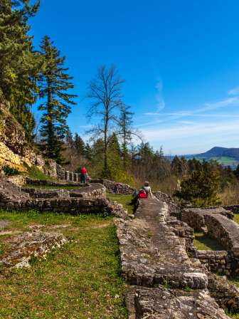 Historische Mauern der Ruine Alt-Tierstein mit Besuchern und Blick über die bewaldete Hügellandschaft im Jurapark.