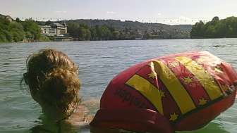 Frau schwimmt mit Wickelfisch von Rheinfelden im Rhein.