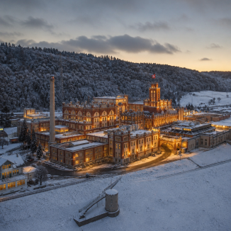 Beleuchtete historische Schlossanlage von Feldschloesschen in einer verschneiten Landschaft bei einsetzender Abenddaemmerung.