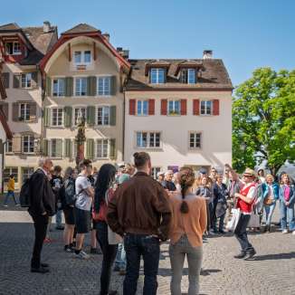 Gruppe mit Stadtführung auf dem Kirchplatz mit dem Gerechtigkeitsbrunnen.