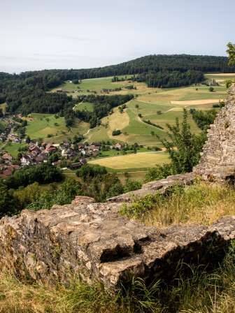 aussicht von der ruine schenkenberg ueber das dorf und die gruenen huegel des juraparks aargau.