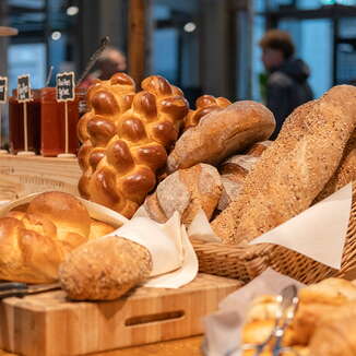 Frische Brote, goldbraune Zöpfe und knusprige Brötchen auf einem rustikalen Brunchbuffet im AHA Aarau.