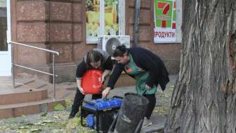 Ukraine – Odessa – 17.11.2024: Zwei Frauen betanken einen Generator auf der Straße, um während eines Stromausfalls einen Laden weiter zu betreiben © Nataliia Mykhailenko / ukrainianphotodiary.org